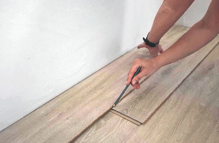 Person kürzt Laminat mit Bleistift